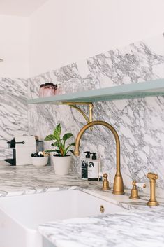 a kitchen with marble counter tops and gold faucets