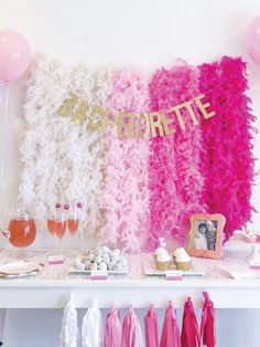 a table topped with pink, white and gold party decorations next to balloons on the wall