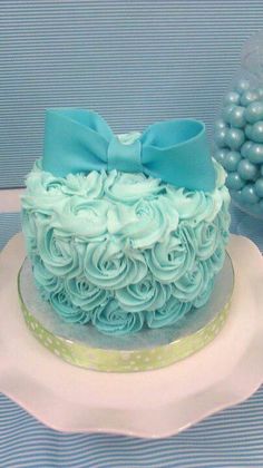 there is a cake with blue frosting and a bow on the top, sitting on a plate