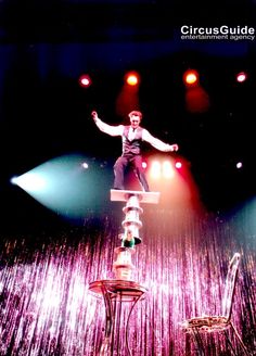 a man standing on top of a table in the middle of a stage with two chairs