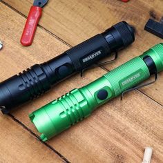 two green flashlights sitting on top of a wooden table