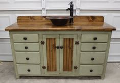 a sink sitting on top of a wooden counter next to a white garage door with a black faucet