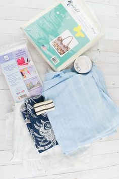 the contents of a sewing project laid out on a white wooden floor, including clothing and accessories