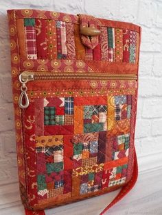 a handbag made out of patchwork fabric with a red string hanging from it