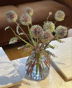 a vase filled with lots of flowers on top of a table next to a couch