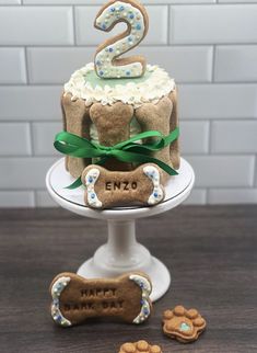 a dog themed birthday cake on a pedestal with cookies and biscuits around the top tier