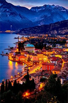 an aerial view of a city at night with mountains in the background and lights on