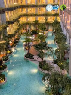 an indoor swimming pool in the middle of a building with lots of trees and plants