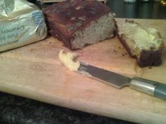 a cutting board with some food on it and a knife sitting next to the cake