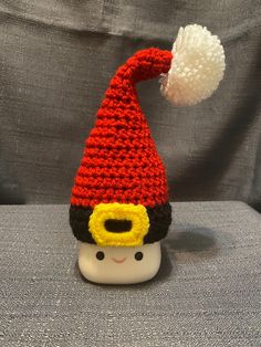 a crocheted gnome hat sitting on top of a white cup with a pom - pom