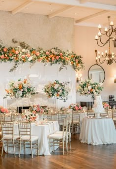 an elegant wedding reception setup with flowers and greenery on the wall, chandelier and fireplace