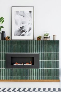 a fireplace in a living room with green tiles on the wall and potted plants next to it