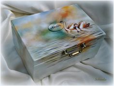 a painted box sitting on top of a white cloth covered bed with the lid open