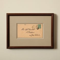 an old postcard is hanging on the wall next to a framed piece of paper