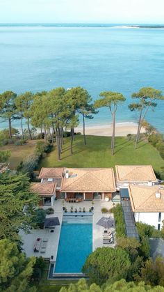 an aerial view of a house with a swimming pool in the foreground and trees surrounding it