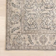 an antique rug on a wooden floor with white and gray accents, including a floral design