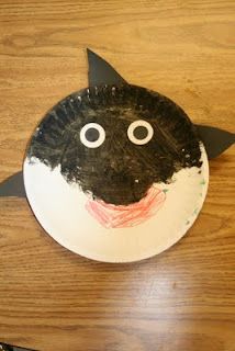 a paper plate with a black and white cat on it's face sitting on a wooden table