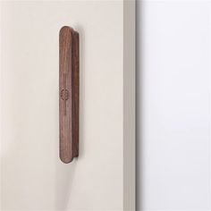 a wooden object hanging on the wall next to a white wall with an arrow in it