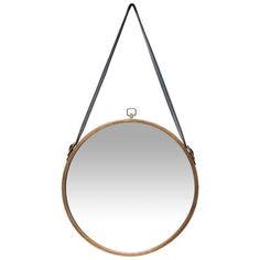 a round mirror hanging on a wall with a leather strap around the edge and a metal hook at the bottom