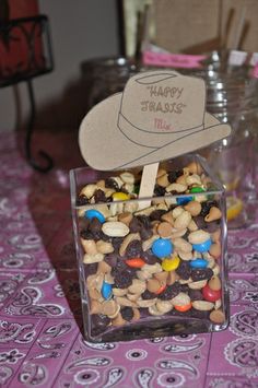 a glass container filled with candy and nuts on top of a purple tablecloth covered table