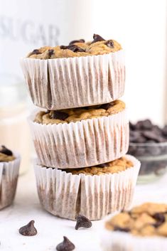 three chocolate chip muffins stacked on top of each other in front of some cookies