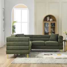 a living room with a large green couch and white rug on the wooden flooring