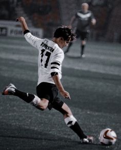 a young man kicking a soccer ball on top of a field