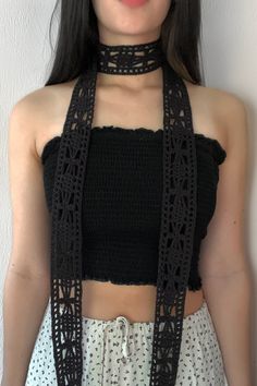 a woman wearing a black crochet halter top and white skirt with her hands in her pockets