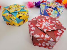 three colorful origami boxes sitting next to each other on a white counter top