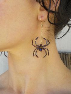 a close up of a person wearing earrings with a spider on it's back