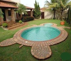 a small pool in the middle of a yard with brick edgings and grass around it