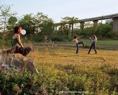 three people are playing frisbee in an open field