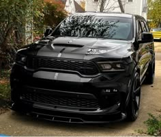 a black dodge suv parked on the side of a road in front of a house