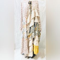 a dress made out of different fabrics hanging on a clothes rack in front of a white backdrop