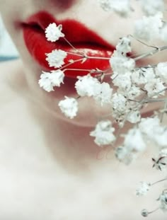 a woman with red lipstick and flowers in her mouth