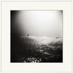 a black and white photo of a person standing in the ocean