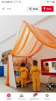 two small children in yellow outfits are looking at an art work on the easel