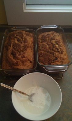 two pans filled with food sitting on top of a counter next to a bowl