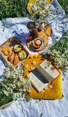 an open book sitting on top of a blanket next to flowers