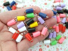 a person is holding many small plastic objects in their hand, all different colors and sizes