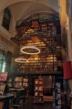 the inside of a library with lots of books on shelves and lights hanging from the ceiling