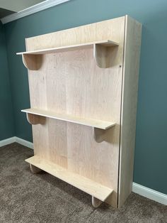 a wooden shelf with two open shelves on the top and bottom, in front of a blue wall