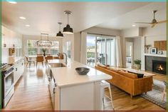 an open concept living room and kitchen area with wood flooring, white walls, large sliding glass doors leading to the balcony