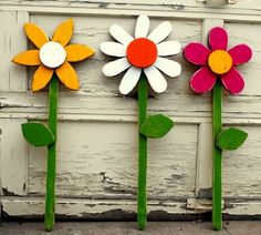 three wooden flowers sitting on top of each other in front of a white door with peeling paint