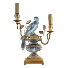 a bird figurine sitting on top of a candelabra with two candles