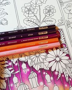 four different colored pencils sitting next to each other on top of a coloring book