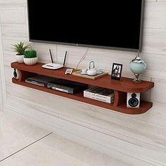 a flat screen tv mounted to the side of a wall next to a wooden shelf