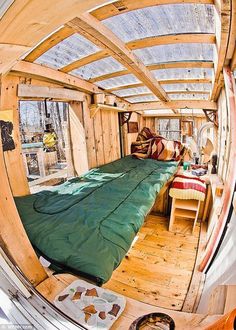 the inside of a tiny house with a bed in it's center and lots of windows