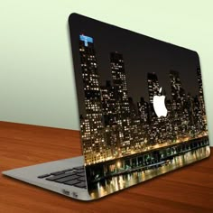 an apple laptop computer sitting on top of a wooden desk in front of a cityscape