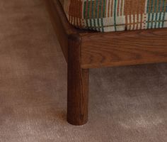 a close up of a wooden bench with a checkered cushion on it's back